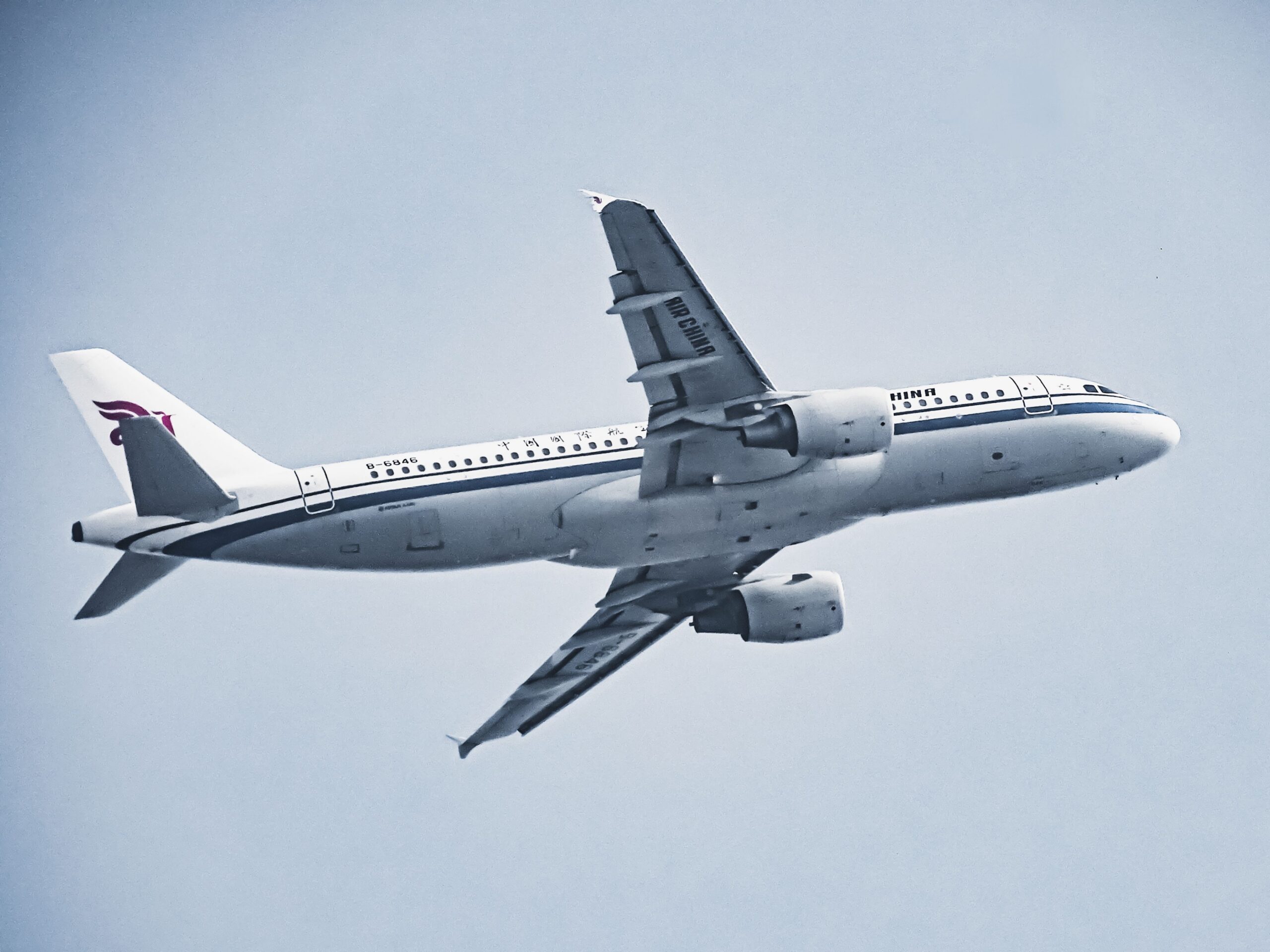 An Air China airplane in flight against a pale blue sky, showcasing aviation and travel.